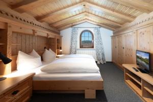 een slaapkamer met een groot bed en een tv bij Haus Bergrausch in Krün