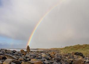a rainbow over a beach with rocks at The Nest at Strandhill in Strandhill
