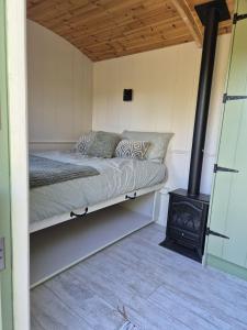 a bed in a room with a wood stove at Clissmann Farm Shepherds Hut in Rathdrum