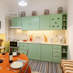 a kitchen with green cabinets and a table with wine glasses at Sofi's Flat in the city center, 5min to the sea in Kalamata