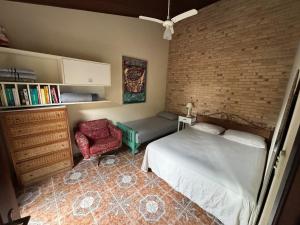 a bedroom with a bed and a chair and a brick wall at Toca do Camarão in São Sebastião +51 photos