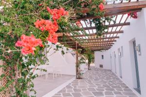 a pergola with red flowers on a building at FarOut - BeachResort & Camping in Mylopotas