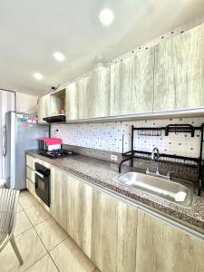 a kitchen with wooden cabinets and a sink at Beachfront Cabin with Private Pool in Puerto Colombia