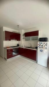 een keuken met rode kasten en een witte koelkast bij Apartment Lela in Pula