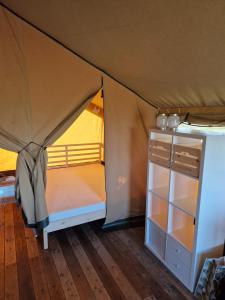 欣德洛彭Glamping Safaritent 4 persoons的帐篷,配有一张床和一个橱柜