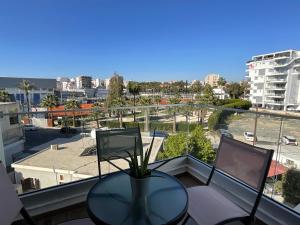 a glass table on a balcony with a view of a city at Le Voyageur II in Larnaca