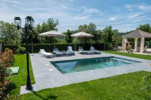 a swimming pool in a yard with chairs and umbrellas at Casa melreiras in Dodro