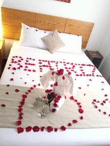 a bed with red rose petals on the bed at Fenix Machupicchu in Machu Picchu