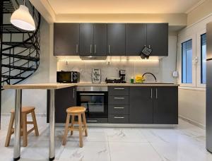a kitchen with black cabinets and a table and stools at Cozy Mytilene Downtown in Mytilene