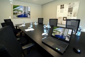a conference room with a table with a laptop on it at Eldorado Flat in Contagem