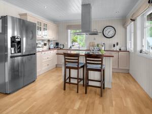 a kitchen with a stainless steel refrigerator and two bar stools at Holiday Home Hyggelia by Interhome in Fossdal
