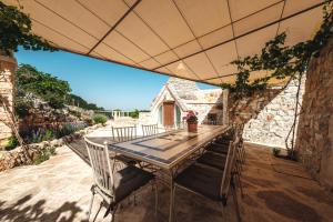 a table and chairs under an umbrella on a patio at HelloAPULIA Trulli Flora - Luxury Trulli with Saltwater Pool and Garden, Noci in Noci