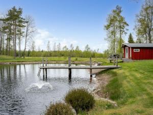 a dock in the middle of a lake with a red building at Holiday Home Lövåsen by Interhome in Bottnaryd