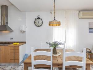 a kitchen with a table and chairs and a clock on the wall at Villa Sueño IV by Interhome in L'Ametlla de Mar