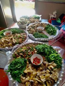 una mesa con varias bandejas de diferentes tipos de alimentos en Homestay Hồ Đá A Căng Tả Phìn, en Sa Pa 19 fotos más