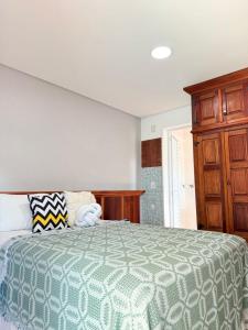 a bedroom with a bed and a wooden cabinet at Studios Vale do Sol in Sao Paulo
