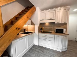 a kitchen with white cabinets and a staircase at Apartment Penia 2-3 by Interhome in Canazei
