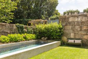 a swimming pool in a garden next to a stone wall at Vandoma in Porto