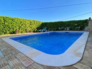 une piscine bleue avec une chaise à côté d'une haie dans l'établissement Vivenda Silvestre Family House, à Albufeira