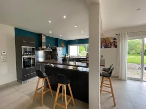 a kitchen with a black counter and stools in it at Maison à louer in Yèvres