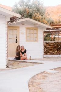 two women sitting in front of a house at FarOut - BeachResort & Camping in Mylopotas