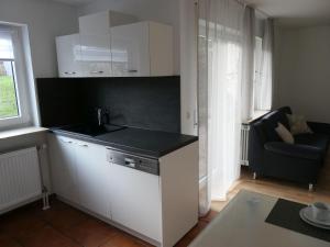 a kitchen with white cabinets and a black counter top at Ferienwohnung Schneckenhaus in Ofterdingen
