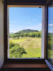 a window with a view of a green field at Charmante maison de village avec jardin, proche abbaye d'Hautecombe in Saint-Pierre-de-Curtille