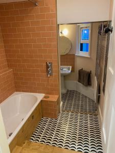 a bathroom with a tub and a tiled floor at Artists Seaside Sanctuary in St. Leonards +28 photos