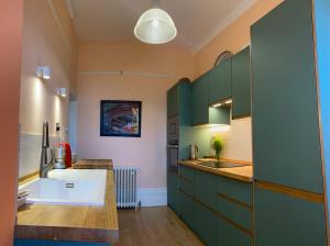 a kitchen with green cabinets and a sink at Artists Seaside Sanctuary in St. Leonards