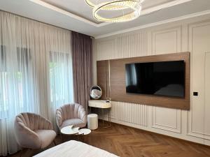 ファガラシュにあるHorace Exclusive Residence Fagarasのベッドルーム(テレビ、椅子2脚、ベッド1台付)