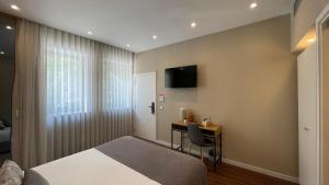 a bedroom with a bed and a desk and a television at MyTrip Porto in Matosinhos