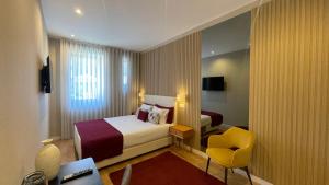 a hotel room with a bed and a yellow chair at MyTrip Porto in Matosinhos
