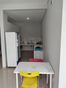a kitchen with a white table and two yellow chairs at Menepi Bali in Uluwatu
