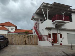 a white house with red balconies and a fence at Menepi Bali in Uluwatu