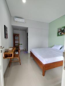 a bedroom with a bed and a wooden desk at Menepi Bali in Uluwatu