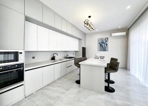 a kitchen with white cabinets and a table and chairs at Qafqaz Modern Harmony in Gabala