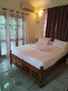 ein Bett mit einem hölzernen Kopfteil in einem Zimmer mit Fenstern in der Unterkunft the 3BHK beach villa near colva beach in Colva