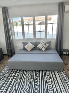 a bed with pillows on it in a room with windows at Chalet con piscina privada cerca del mar in Cala'n Bosch