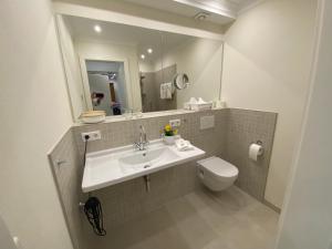 a bathroom with a sink and a toilet and a mirror at Charmantes Einzelzimmer in Odenthal