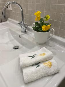 a bathroom sink with two towels and a vase with yellow flowers at Charmantes Einzelzimmer in Odenthal
