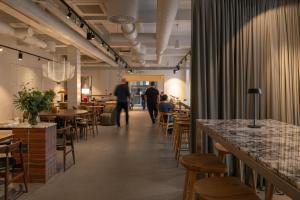Ein Restaurant mit Tischen und Stühlen und Menschen im Hintergrund in der Unterkunft Corner Hotel in Vilnius