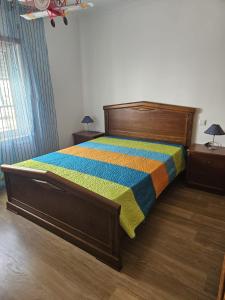 a bedroom with a wooden bed with a colorful bedspread at BigWaves2 in Nazaré