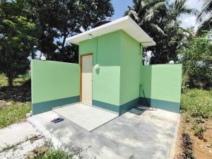 a green house with a white roof and a door at Hijau Harmoni Stay in Mersing