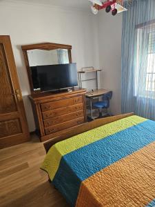 a bedroom with a bed and a dresser with a television at BigWaves2 in Nazaré