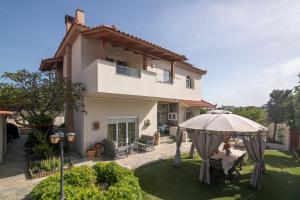 a villa with an umbrella and a yard with a house at Villa Anel - A peaceful retreat in Néa Alikarnassós