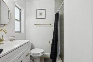 a white bathroom with a toilet and a sink at 3BR Orlando Stay Save 16 Pet-Friendly Fun in Orlando +16 photos