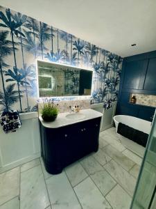 a bathroom with a sink and a tub and palm trees wallpaper at Tuns House B&B in Eggleston +22 photos