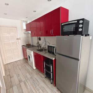 a kitchen with red cabinets and a refrigerator at Eldorado MILE STUDIO in Playa de las Americas