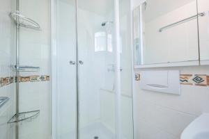a white bathroom with a shower and a toilet at Ferienwohnpark Immenstaad am Bodensee Nurdachhaus Typ 7 ND 04 in Immenstaad am Bodensee +16 photos