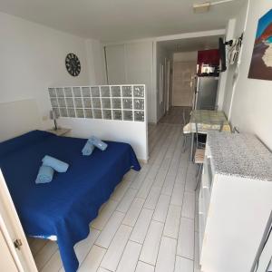 a bedroom with a blue bed and a kitchen at Eldorado MILE STUDIO in Playa de las Americas